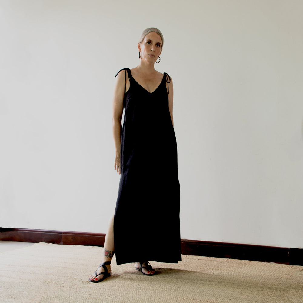 Woman wearing the Teia Dress sewing pattern from Pattern Fantastique on The Fold Line. A sleeveless dress pattern made in linen, silk, rayon, or tencel fabric, featuring a deep V-neckline, long tie straps, side splits, and maxi length.