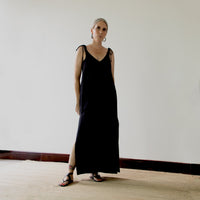 Woman wearing the Teia Dress sewing pattern from Pattern Fantastique on The Fold Line. A sleeveless dress pattern made in linen, silk, rayon, or tencel fabric, featuring a deep V-neckline, long tie straps, side splits, and maxi length.