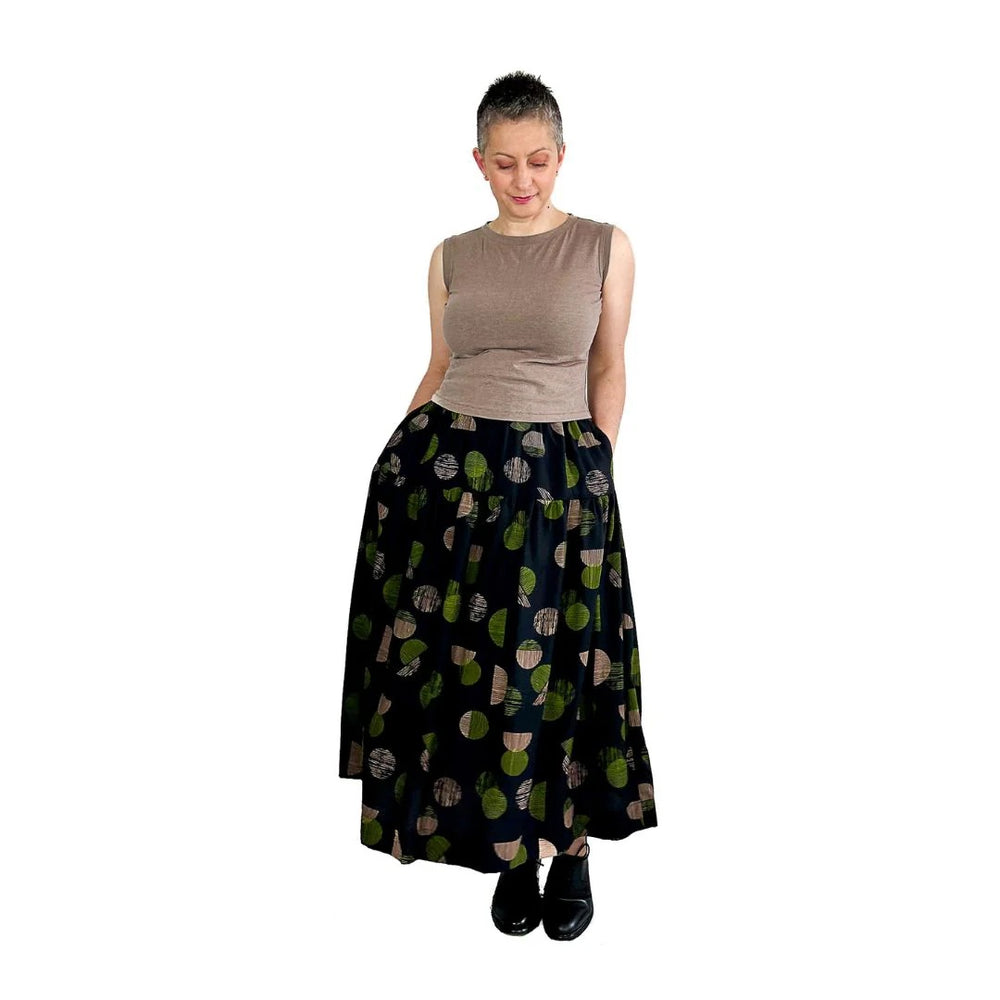 Woman wearing the Tia Skirt sewing pattern from Dhurata Davies Patterns on The Fold Line. A skirt pattern made in linen and linen blends, tencel, viscose, cotton lawn, double gauze, or lightweight poplin fabric, featuring a relaxed fit, elasticated waist, two tiers, in-seam pockets, and midi length.