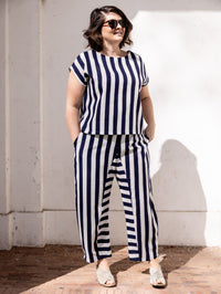 Woman wearing the Tiki Trousers sewing pattern from Notches on The Fold Line. A trousers pattern made in denim, linen, seersucker, canvas, or cotton twill fabric, featuring a relaxed fit, elastic waistband, mock fly, side pockets, and ankle length.