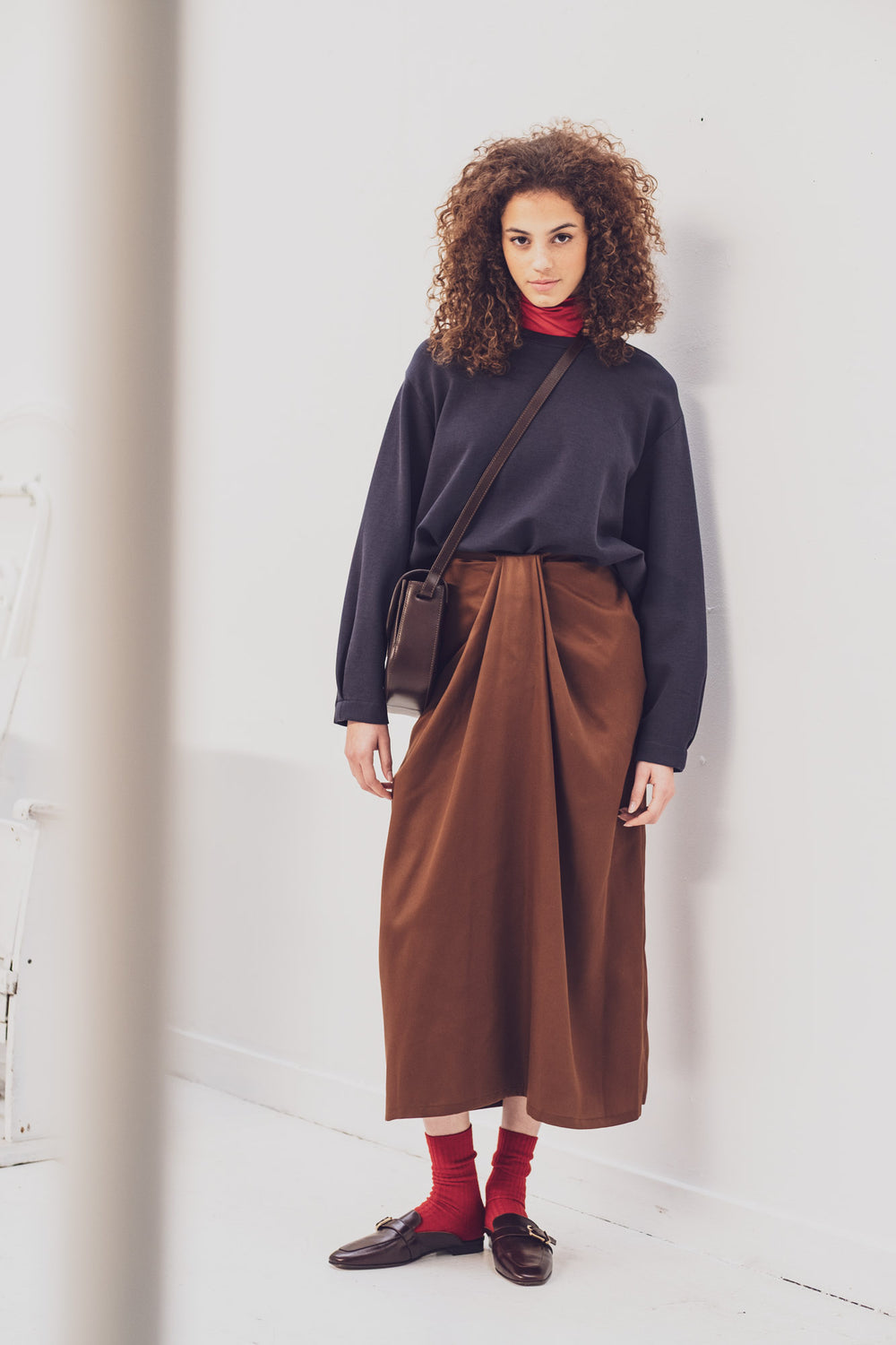 Woman wearing the Trina Skirt sewing pattern from Fibre Mood on The Fold Line. A skirt pattern made in cotton twill, cotton satin, light wool, linen blend, or lyocell fabric, featuring a centre front pleat detail, pockets, and midi length.