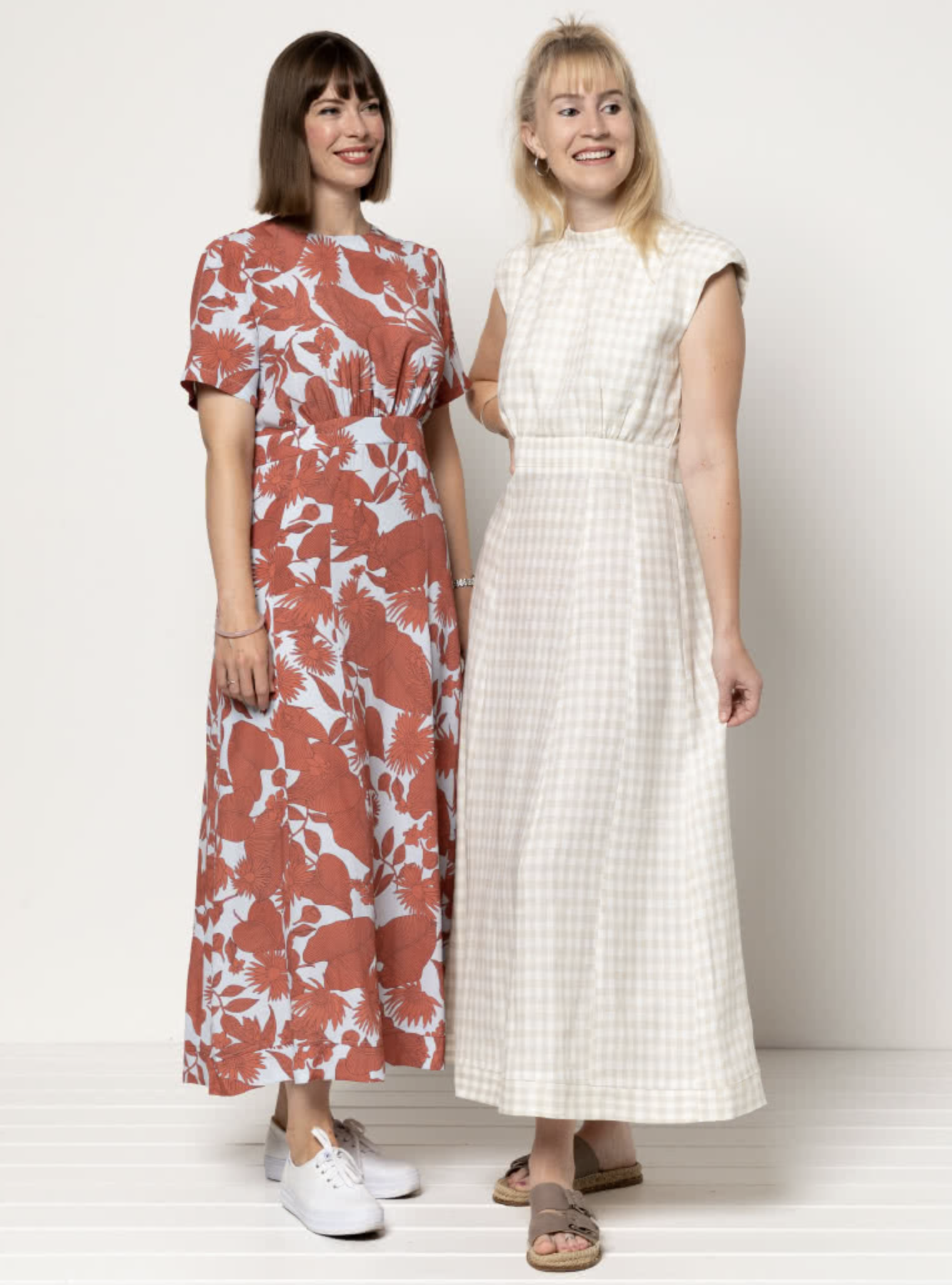 Women wearing the Trinnie Woven Dress sewing pattern from Style Arc on The Fold Line. A dress pattern made in linen, crepe, silk, rayon, or cotton fabric, featuring a round neckline, sleeveless or short sleeves, waistband, 11-panel gored skirt, and ankle length.
