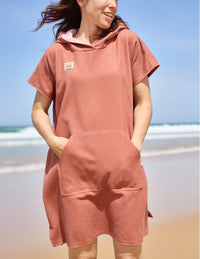 Woman wearing the Tropique Poncho sewing pattern from Atelier Scämmit on The Fold Line. A beach cover up pattern made in cotton, bamboo, terrycloth, microfibre, or waffle weave fabric, featuring a hood, kangaroo pocket, and side opening for easy changing.