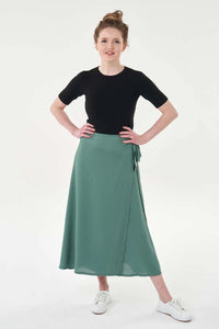 Woman wearing the Ultimate Wrap Skirt sewing pattern from Sew Over It on The Fold Line. A wrap skirt pattern made in cotton, cotton lawn, or viscose fabric, featuring waist ties and a midi length.