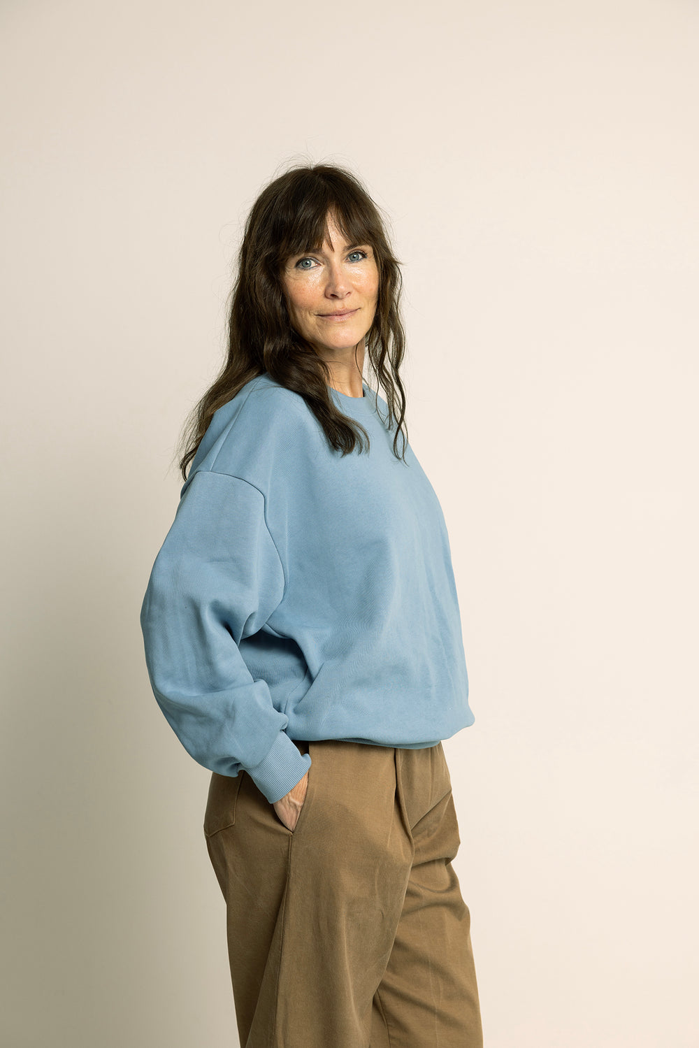 Woman wearing the Unisex Boyfriend Sweater sewing pattern from Wardrobe by Me on The Fold Line. A sweatshirt pattern made in French terry fabric, featuring an oversized fit, dropped shoulders, and ribbing at the neckline, cuffs and hem.