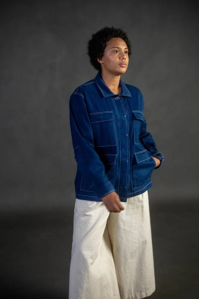 Woman wearing the Unisex Paynter Jacket sewing pattern from Merchant & Mills on The Fold Line. A workwear style jacket pattern made in cotton twill, denim, wool, or dry oilskin fabric, featuring a collar, button placket, long sleeves, large patch pockets with flaps, and topstitching.