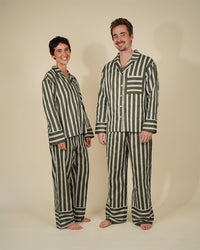 Man and woman wearing the Unisex Pyjama Set sewing pattern from Wardrobe by Me on The Fold Line. A pyjamas pattern made in cotton fabric, featuring a relaxed fit shirt with a convertible collar, dropped shoulders, long sleeves, button front, and chest pocket, and pants with an elastic waist and back pocket.