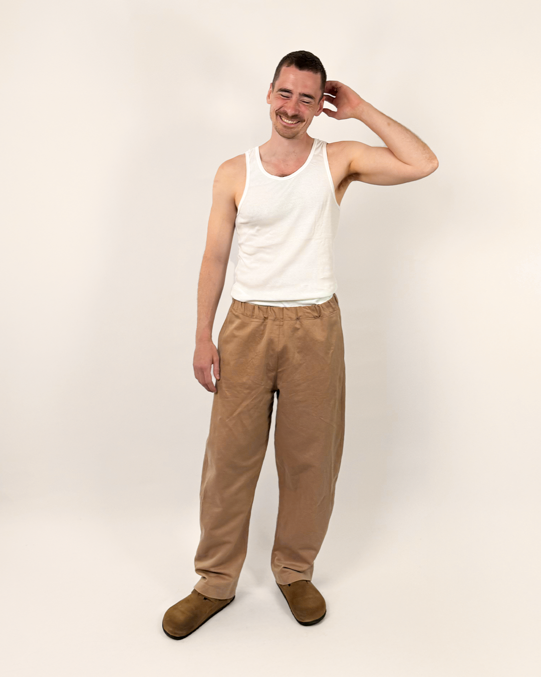 Man wearing the Unisex Volume Pants sewing pattern from Wardrobe by Me on The Fold Line. A trousers pattern made in cotton, linen, denim, corduroy, or canvas fabric, featuring an elastic waist, side and back pockets, curved side seam, and barrel leg.