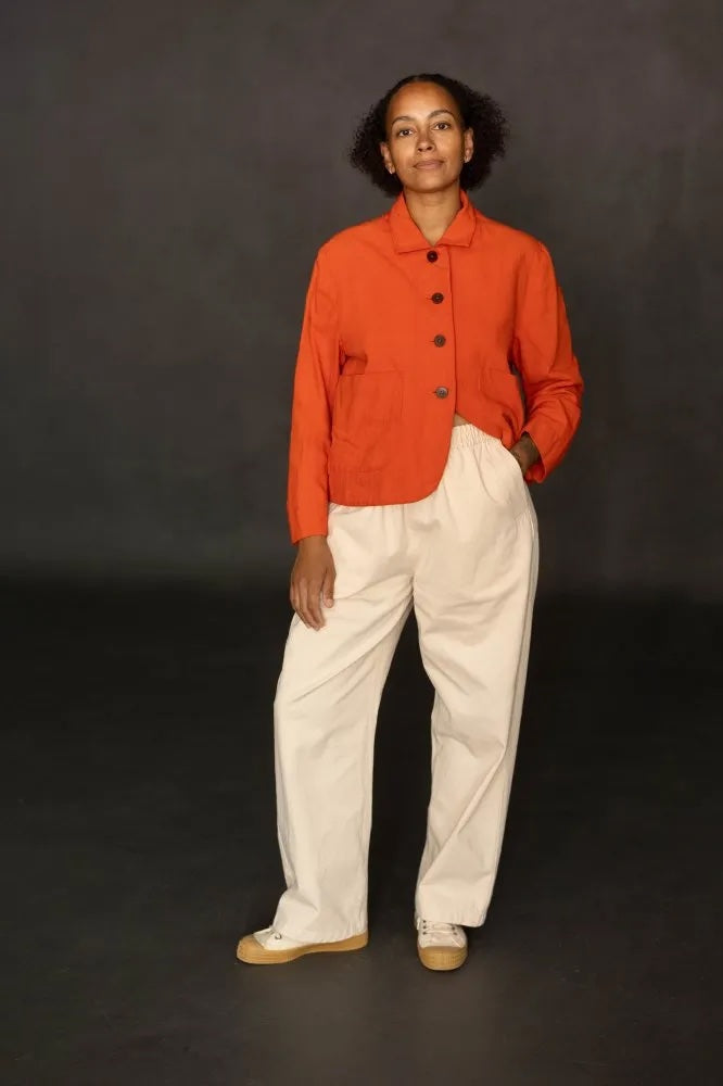 Woman wearing the Unisex Wednesday Trousers sewing pattern from Merchant & Mills on The Fold Line. A mid-rise trousers pattern made in cotton, denim, corduroy, linen, or hemp/cotton blend fabric, featuring an elastic waist, slanted front pockets, back patch pocket, and straight leg cut.