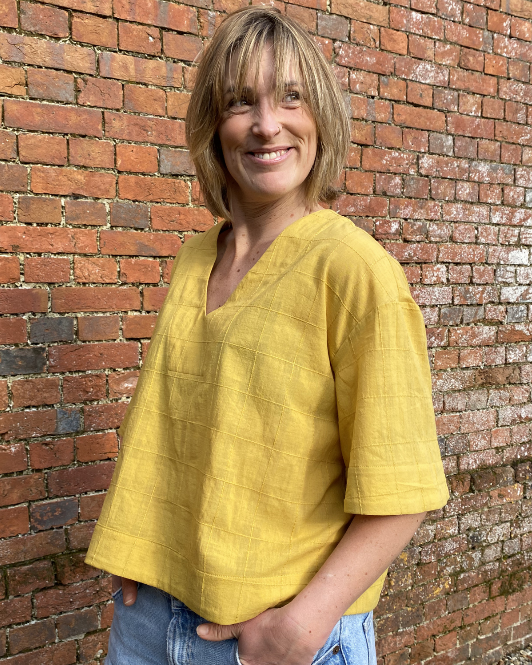 Woman wearing the V-neck Top sewing pattern from The Avid Seamstress on The Fold Line. A top pattern made in cotton lawn, linen, viscose, chambray, or lightweight denim fabric, featuring a relaxed fit, V-neckline, and mid-length sleeves.