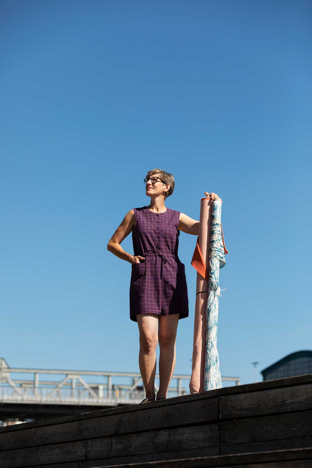 Woman wearing the Veranda Jumpsuit sewing pattern from TAUKO on The Fold Line. A sleeveless playsuit pattern made in cotton, linen, tencel, double gauze, or velvet fabric, featuring a round neckline, button front, drawstring waist, patch pockets, and shorts length.