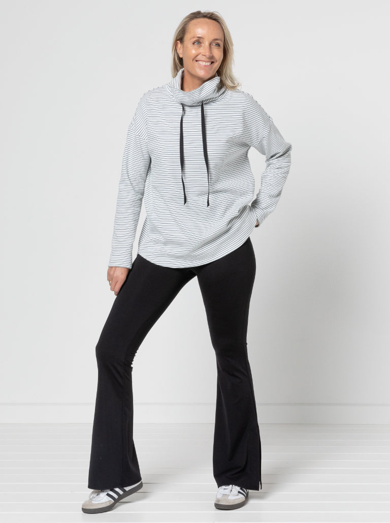 Woman wearing the Verity Knit Top sewing pattern from Style Arc on The Fold Line. A top pattern made in sweater knit, rugby, or fleece fabric, featuring a funnel neck with a drawstring, dropped shoulders, long sleeves, and a slightly scooped hemline.