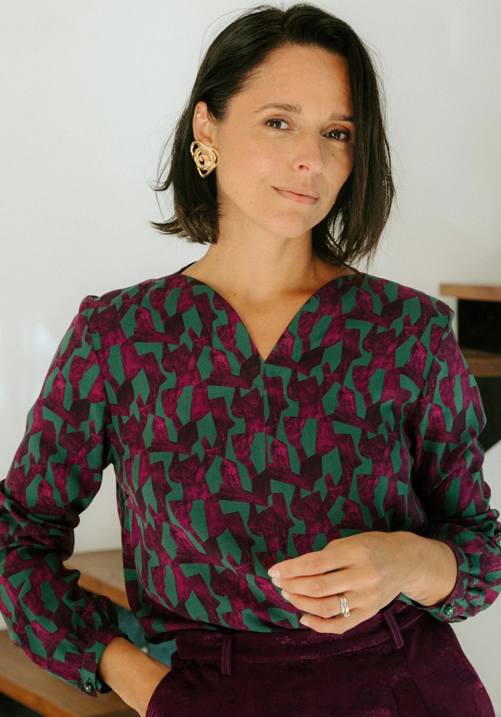 Woman wearing the Volata Blouse sewing pattern from Maison Fauve on The Fold Line. A top pattern made in poplin, crepe, voile, lace, lightweight denim, or chambray fabric, featuring a straight cut, curved V-neckline at the front and back, and long sleeves.