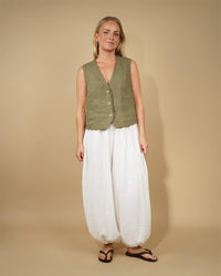 Woman wearing the Waistcoat Top sewing pattern from Wardrobe by Me on The Fold Line. A sleeveless top pattern made in cotton or linen fabric, featuring a deep V-neckline and three-button front closure.
