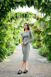 Woman wearing the Wavy Hem Dress & Slim Sleeve sewing pattern bundle from Puff and Pencil on The Fold Line. A dress pattern made in stretch mesh, fine cotton rib, or jersey fabric, featuring a body-hugging fit, boat neckline, long sleeves, and wavy hem.