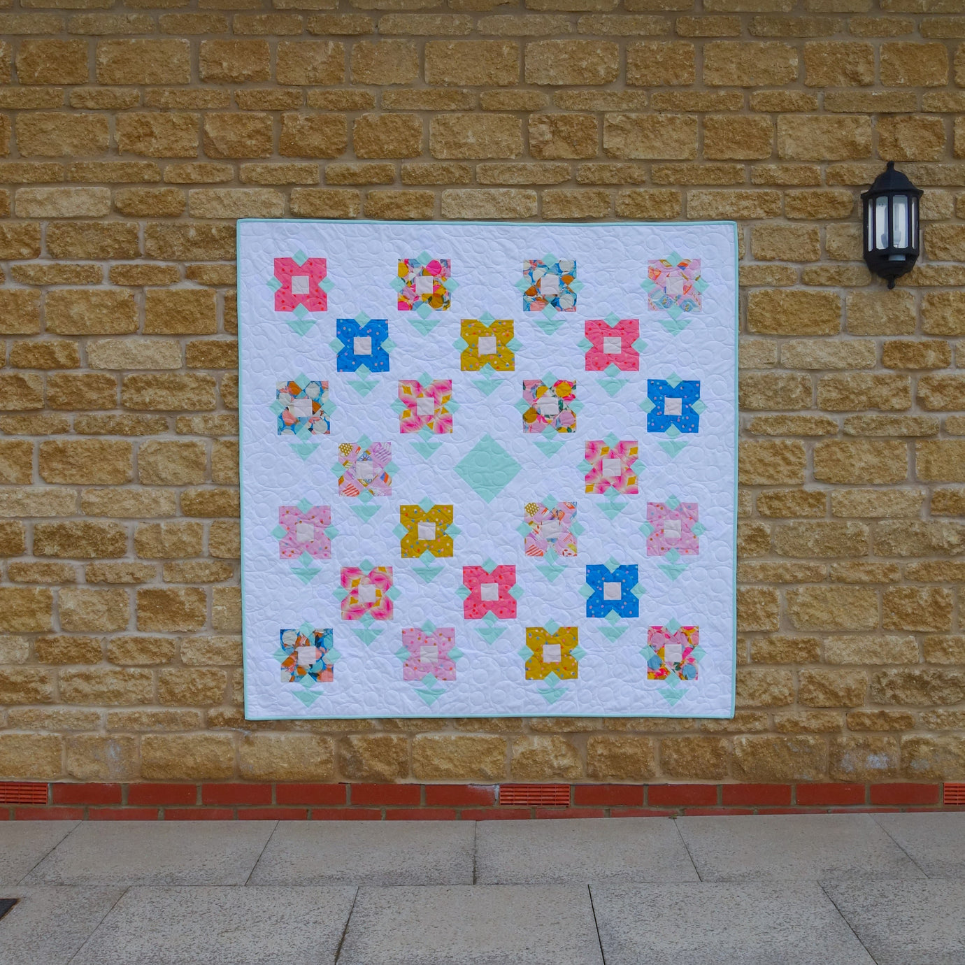 The Wildflower Meadow Quilt sewing pattern from Lou Orth Designs on The Fold Line. A quilt pattern made in quilting cotton fabric, featuring flower blocks arranged on point.