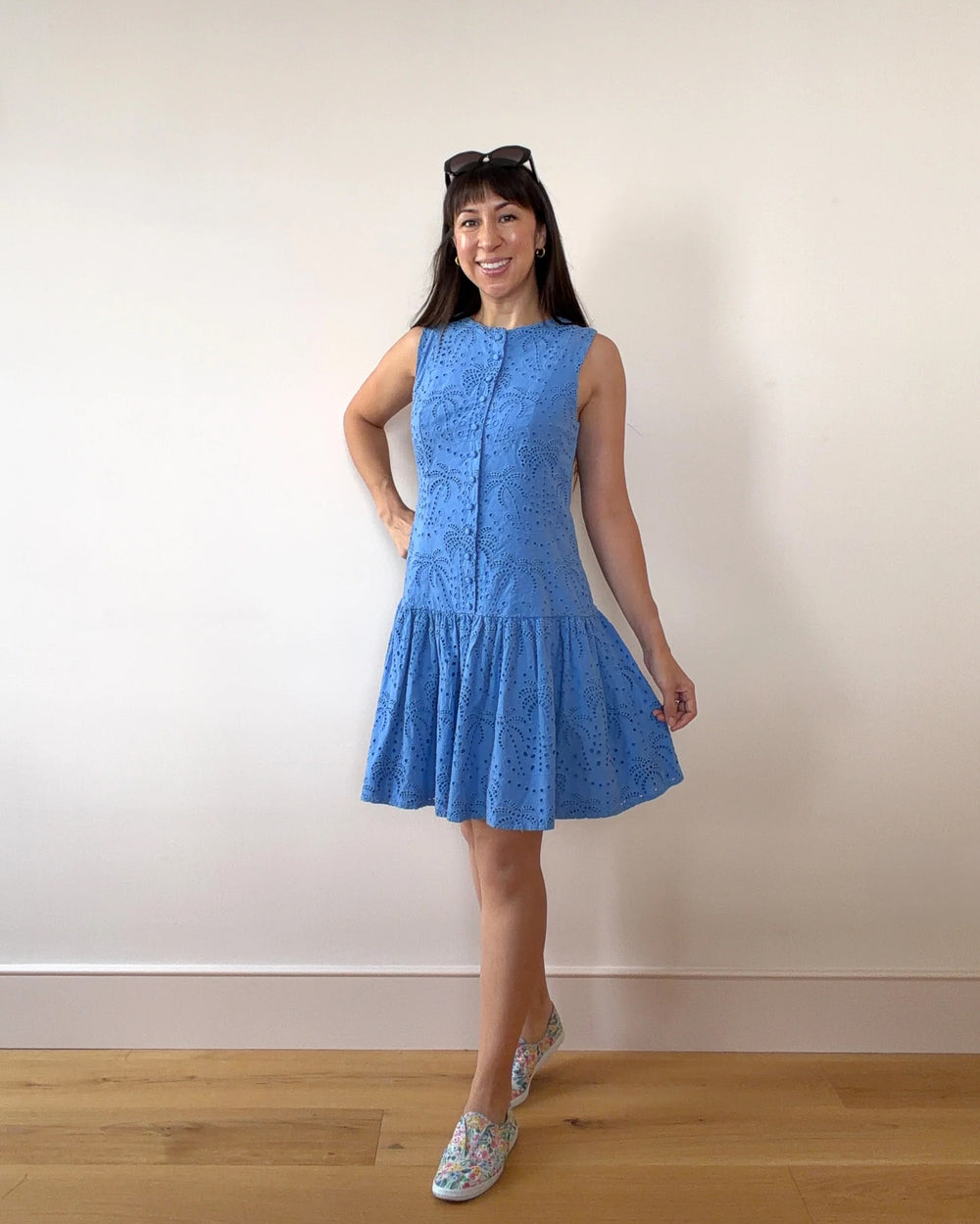 Woman wearing the Wimbledon Drop-Waist Dress sewing pattern from Nina Lee on The Fold Line. A sleeveless dress pattern made in cotton lawn, cotton poplin, crepe, chambray, lightweight wool, or lightweight needlecord fabric, featuring a fitted bodice with a faux button front, invisible zipper at the back, and short gathered skirt.
