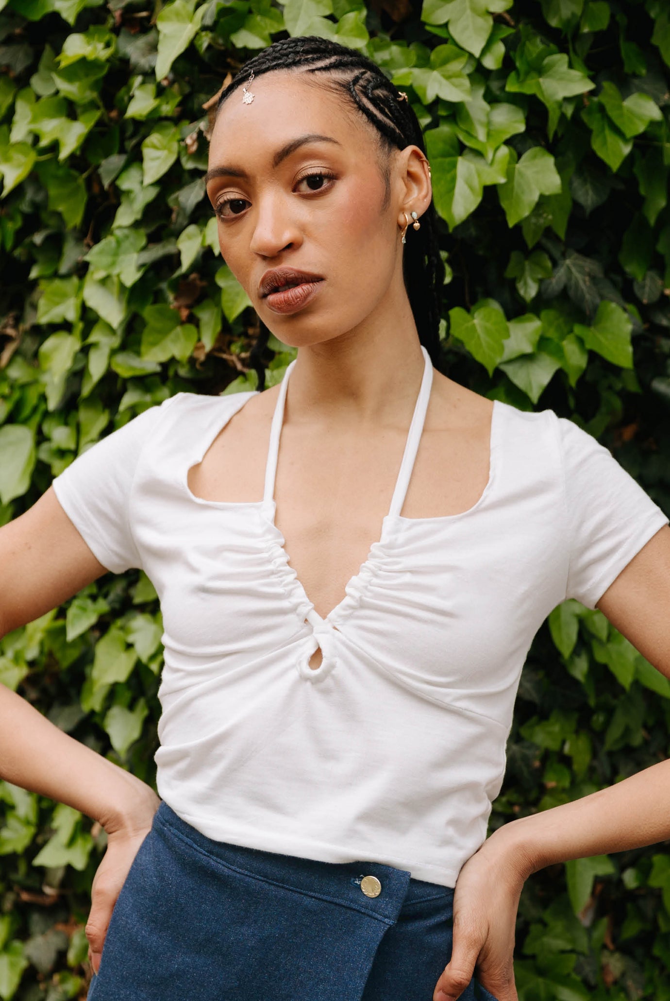 Woman wearing the Winnie Top sewing pattern from JULIANA MARTEJEVS on The Fold Line. A top pattern made in cotton jersey fabric, featuring short sleeves, underbust seams, and a low neckline with a cut-out and halterneck ties.