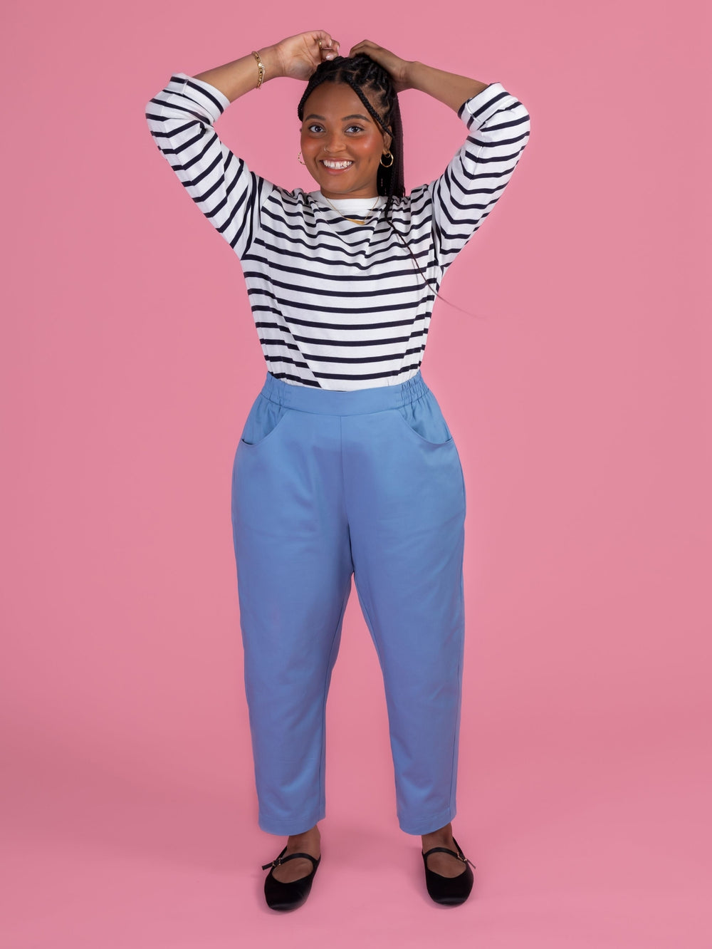 Woman wearing the Winnie Trousers sewing pattern from Tilly and the Buttons on The Fold Line. A trousers pattern made in cotton twill, chambray, washed linen, double gauze, or needlecord fabric, featuring a high waist, flat-fronted elasticated waistband, pockets, barrel leg, and ankle length.