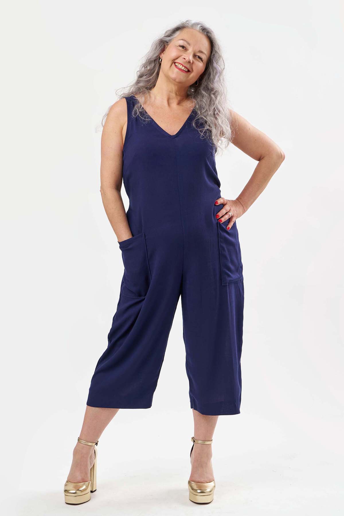 Woman wearing the Winona Jumpsuit sewing pattern from Sew Over It on The Fold Line. A sleeveless jumpsuit pattern made in cotton poplin, chambray, linen, or viscose fabric, featuring a V-neckline, bust darts, cropped leg, patch pockets, and relaxed fit. 