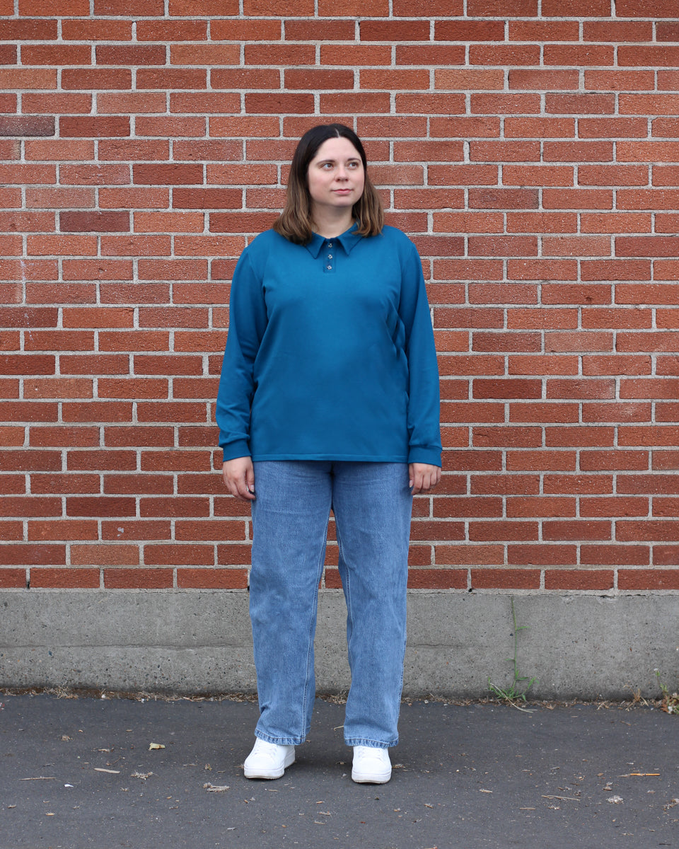 Woman wearing the Women's Sombrio Polo sewing pattern from Thread Theory on The Fold Line. A polo shirt pattern made in knit fabric, featuring a relaxed fit, pointed collar, partial button placket, and long sleeves.