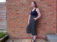Woman wearing the Women's Waratah Wide Leg Pants sewing pattern from Waves & Wild on The Fold Line. A pants pattern made in viscose, rayon, silk, poplin, lawn, linen blend, or chambray fabric, featuring an elasticated waist with a flat front, front pleats, high rise, pockets, and cropped legs.