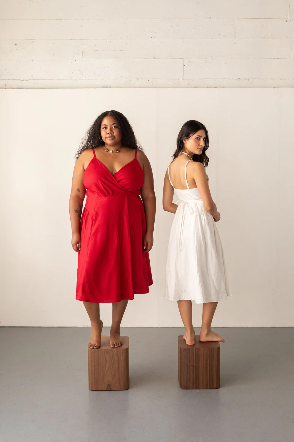 Women wearing the Wren Wrap Dress sewing pattern from Friday Pattern Company on The Fold Line. A dress pattern made in rayon challis, silk, lawn, voile, or linen fabric, featuring a V-neckline, lined bodice, adjustable spaghetti straps, panelled skirt with gathering on the sides, and below-knee length.