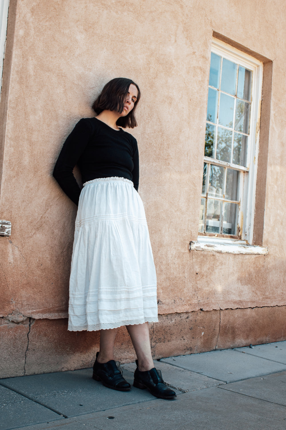 Woman wearing the Zamora Skirt sewing pattern from Madswick on The Fold Line. A skirt pattern made in linen, cotton, or tencel fabric, featuring an elasticated waistband, two gathered tiers, pintucks, and midi length.