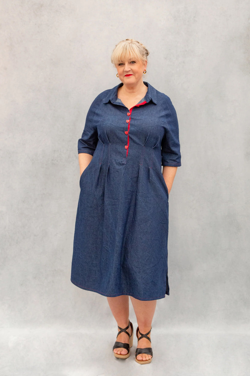 Woman wearing the Zoe Dress sewing pattern from Emporia Patterns on The Fold Line. A shirt dress pattern made in cotton, poplin, linen, linen blends, lawn, chambray, lighter weight denim, viscose challis, or needlecord fabric, featuring a collar with a stand, front button placket, raglan sleeves, pleats at the waist, cutaway pockets, and side splits at the hem.