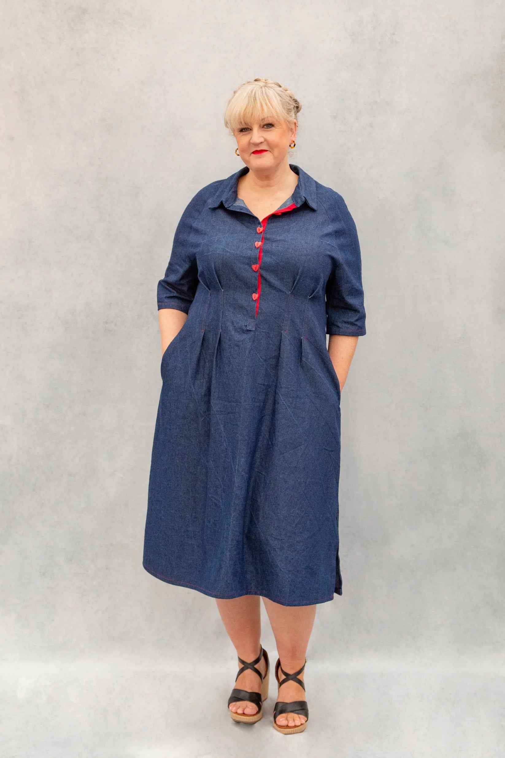 Woman wearing the Zoe Dress sewing pattern from Emporia Patterns on The Fold Line. A shirt dress pattern made in cotton, poplin, linen, linen blends, lawn, chambray, lighter weight denim, viscose challis, or needlecord fabric, featuring a collar with a stand, front button placket, raglan sleeves, pleats at the waist, cutaway pockets, and side splits at the hem.