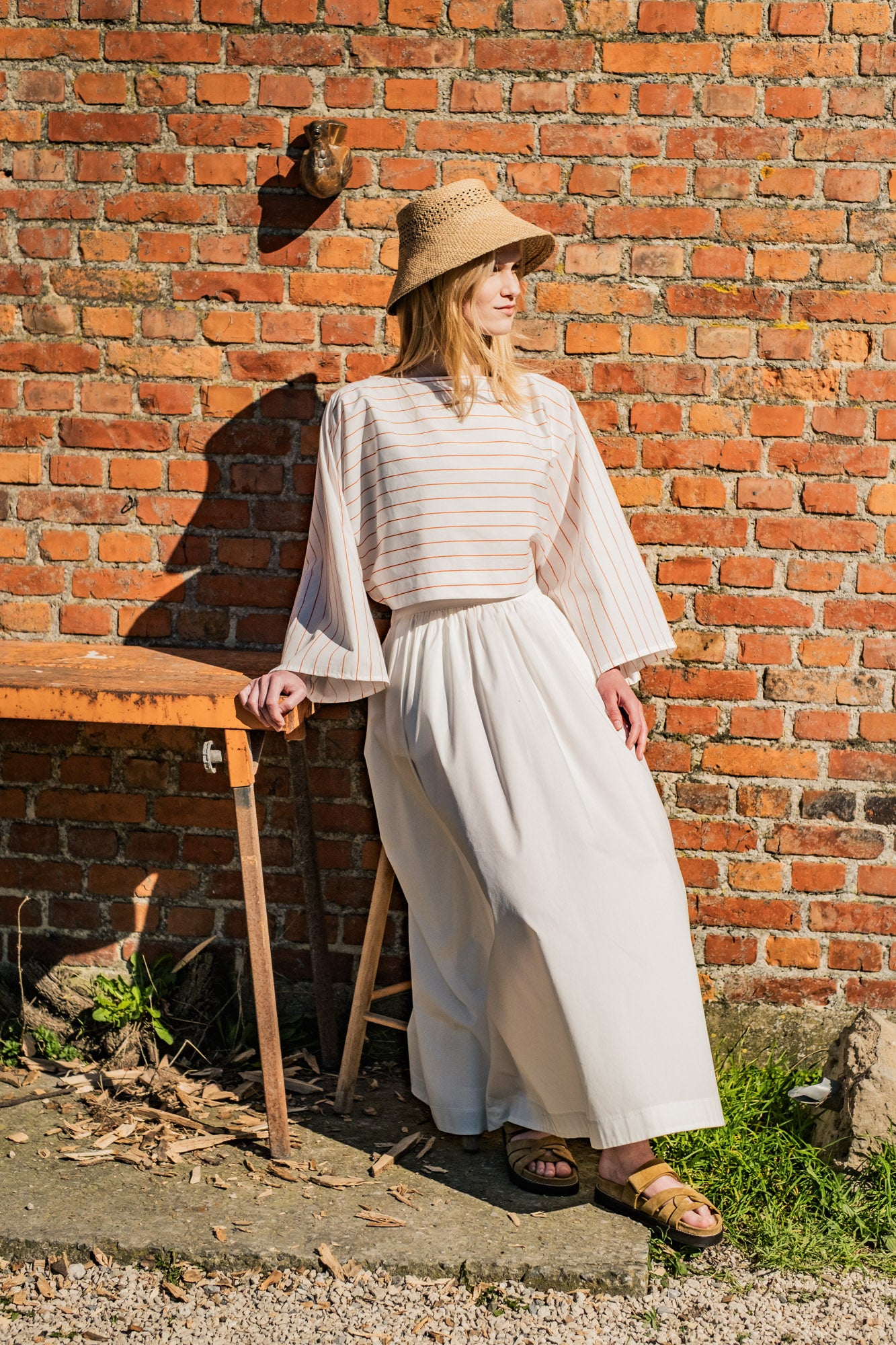 Woman wearing the Zoey Top sewing pattern from Fibre Mood on The Fold Line. A top pattern made in chambray, linen, interlock, French terry, crepe, viscose, or poplin fabric, featuring a boat neck, long grown-on sleeves, and cropped length.