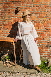 Woman wearing the Zoey Top sewing pattern from Fibre Mood on The Fold Line. A top pattern made in chambray, linen, interlock, French terry, crepe, viscose, or poplin fabric, featuring a boat neck, long grown-on sleeves, and cropped length.