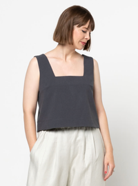 Woman wearing the Byron Woven Top sewing pattern from Style Arc on The Fold Line. A slip-on sleeveless top pattern made in washed linen, rayon, crepe, silk, or cotton fabric, featuring a square neckline, all-in-one facing, bust darts, deep hem facing with