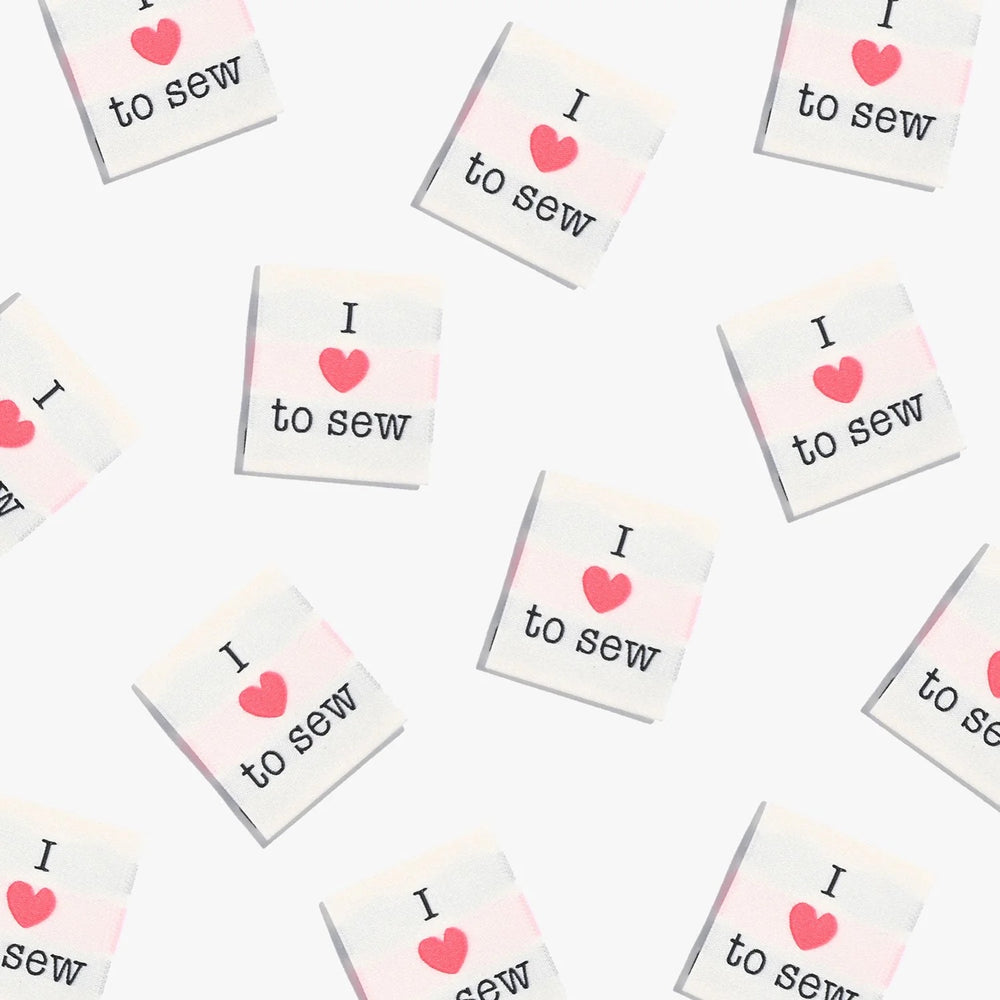 Photo showing 'I Love to Sew' Labels from Kylie & The Machine on The Fold Line. A washable, durable, and non-scratchy label. Included are, 6 woven labels showing a red heart with black writing on a white background. They are all ready to be sewn into your