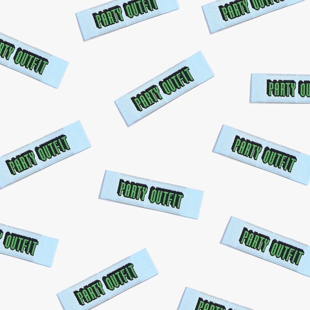 Photo showing 'Party Outfit' Labels from Kylie & The Machine on The Fold Line. A washable, durable, and non-scratchy label. Included are, 6 woven labels with green writing on a pale blue background. They are all ready to be sewn into your handmade clothes