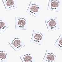 Photo showing 'Sewing on the Brain' Labels from Kylie & The Machine on The Fold Line. A washable, durable, and non-scratchy label. Included are, 6 woven labels showing a brain with black writing on a white background. They are all ready to be sewn into yo