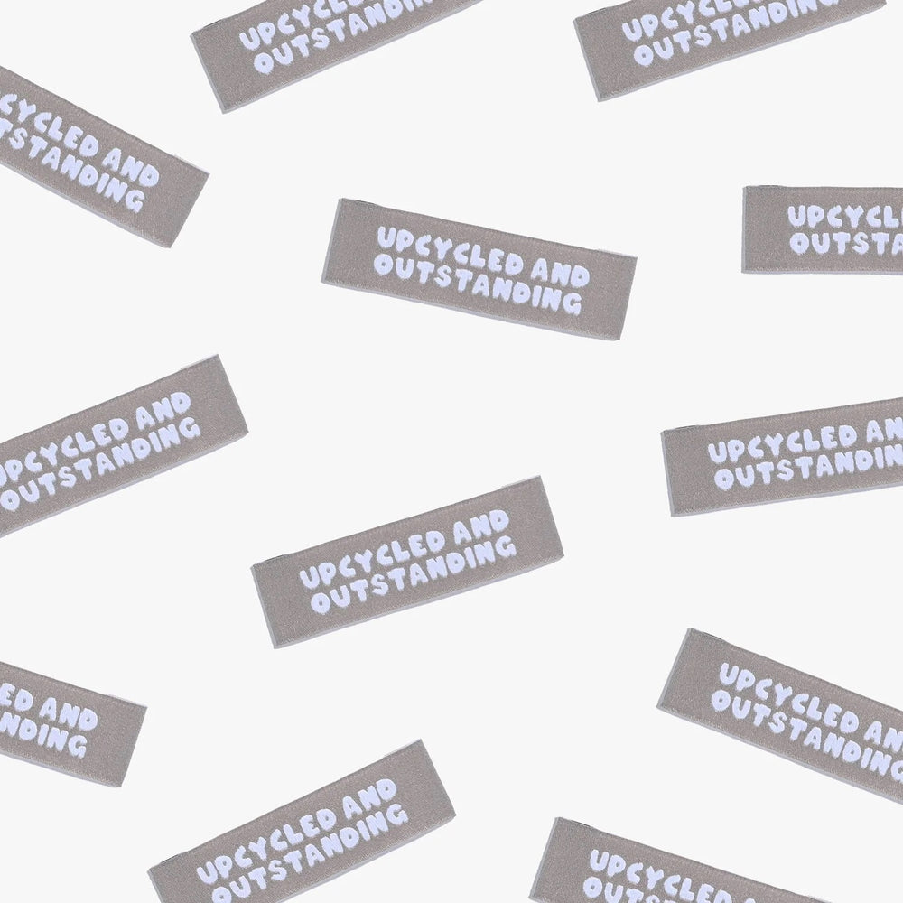 Photo showing 'Upcycled and Outstanding' Labels from Kylie & The Machine on The Fold Line. A washable, durable, and non-scratchy label. Included are, 6 woven labels with white writing on a brown background. They are all ready to be sewn into your handmade