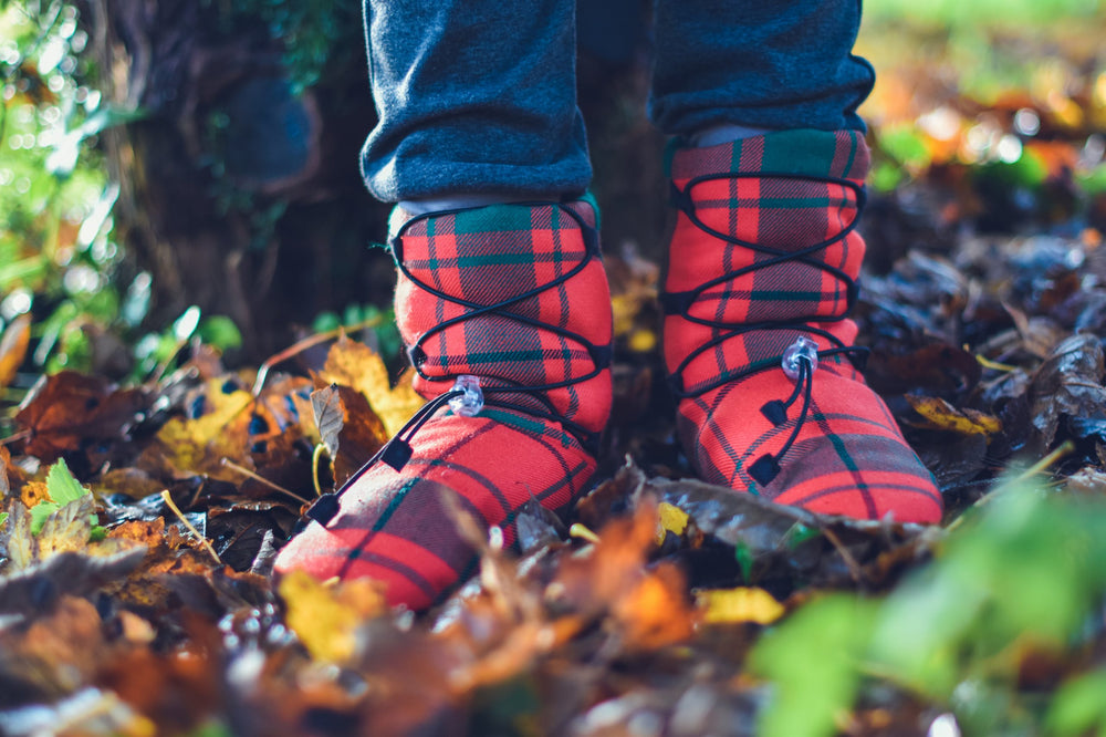 Child wearing the Fireside Slippers sewing pattern from Waves & Wild on The Fold Line. A slipper pattern made in corduroy, denim, wool or velvet fabrics, featuring a cross over tie with toggle fastener, high ankle length and reinforced heel.