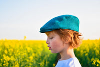 Child wearing the Baby/Child/Adult Fell and Dale Flat Cap sewing pattern by Wavers and Wild. A cap pattern made in wool tweed, wool blends, corduroy, denim or heavier linen fabrics, featuring optional elastic at the back and a brim or peak.