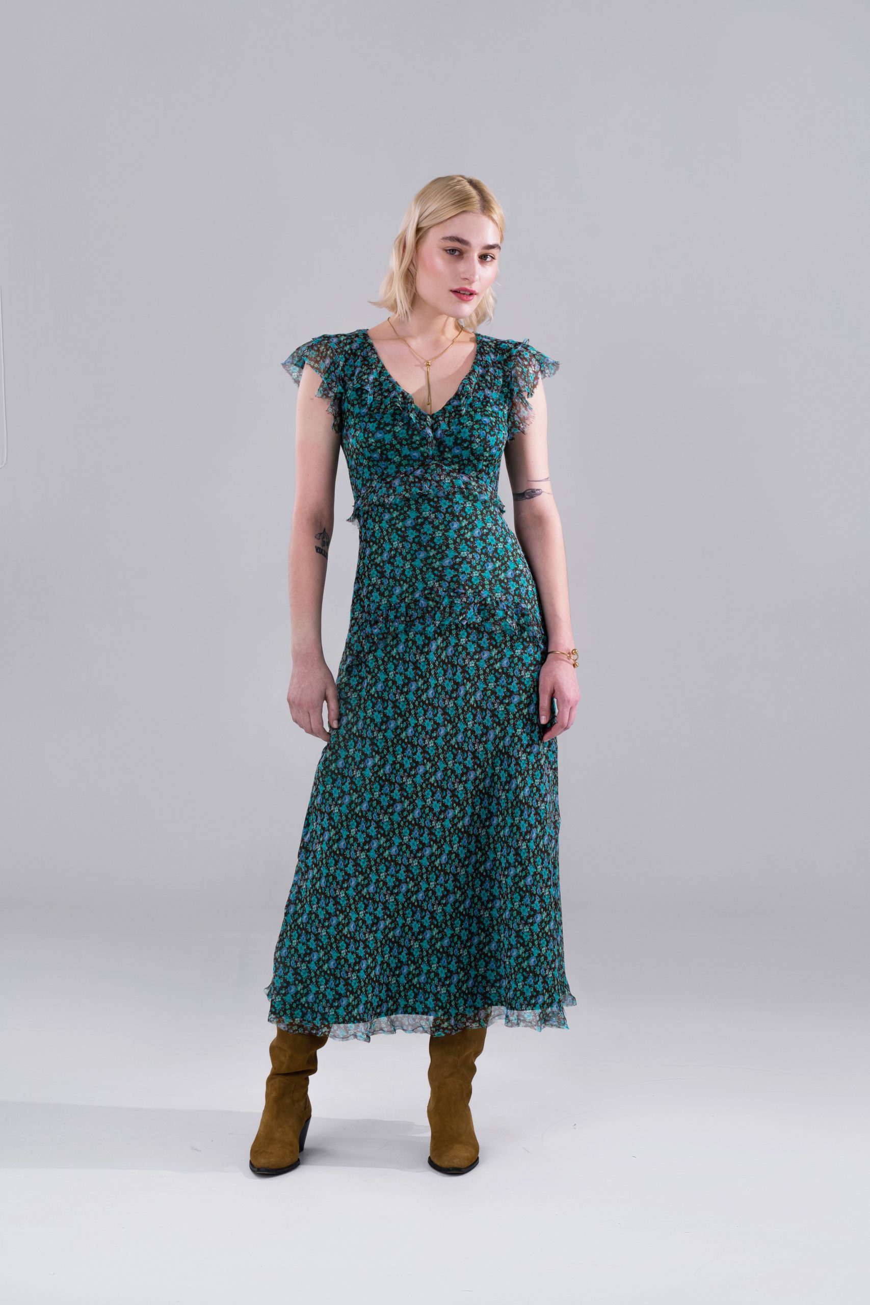 Woman wearing the Caitlin Dress sewing pattern from Vikisews on The Fold Line. A dress pattern made in Atlas, viscose, silk, chiffon, crepe de chine or batiste fabrics, featuring a close-fit, accentuated high waist, deep V-neckline with flounce, short flo