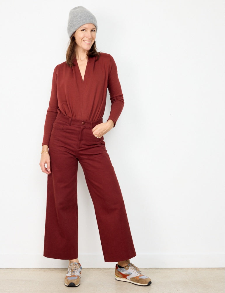 Woman wearing the California Pants sewing pattern from Atelier Scämmit on The Fold Line. A trouser pattern made in serge or denim fabrics, featuring a wide-leg, mid-rise waist, front fob and rounded pockets, topstitched yoke, back patch pockets, fly zip a