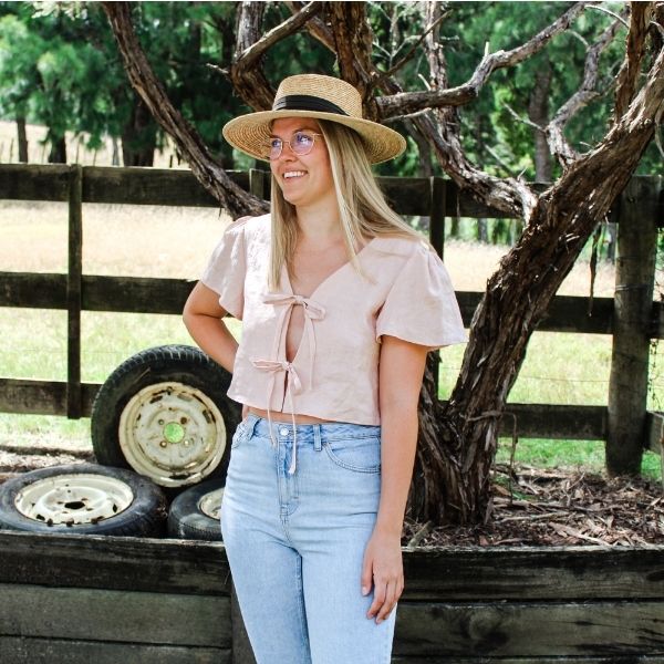 Woman wearing the Camille Top sewing pattern by Makyla Creates. A top pattern made in light to medium weight fabrics such as linens, cottons, silk, tencel or rayon fabrics, featuring a cropped length, loose fit, deep V-neck and two functional ties at the 