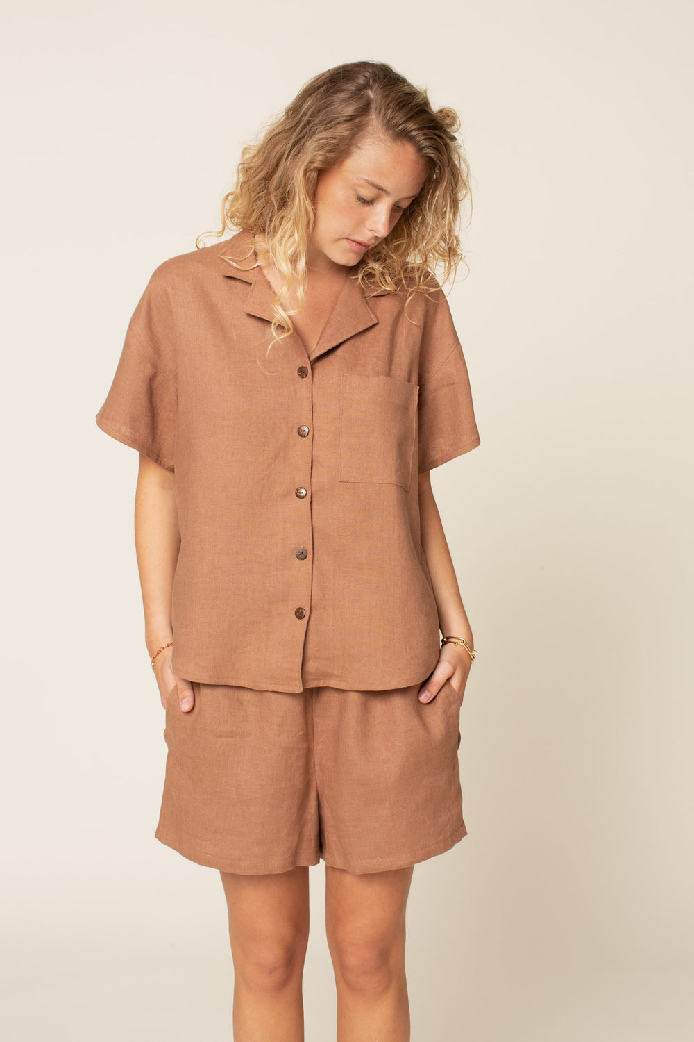 Woman wearing the Camp Shirt and Shorts sewing pattern from Wardrobe by Me on The Fold Line. A shirt and shorts pattern made in cotton, linen, viscose or silk fabrics, featuring a shirt in casual style, button front closure, convertible collar, dropped sh