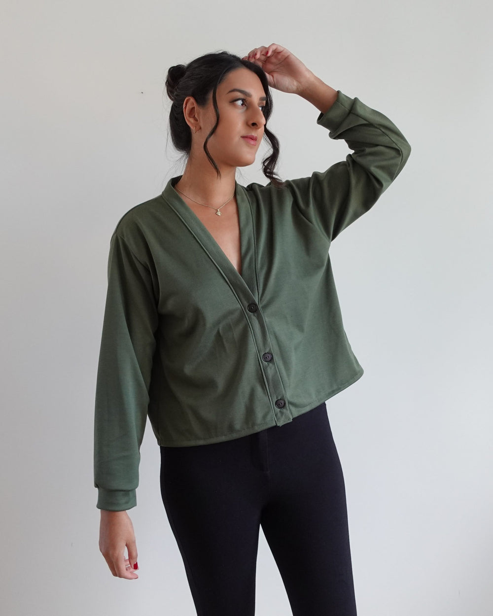 Woman wearing the Cara Cardigan sewing pattern from Tammy Handmade on The Fold Line. A cardigan pattern made in jersey, ribbed knit, sweatshirting, and ponte roma fabrics, featuring a relaxed-fit, dropped shoulders, V-neck, buttoned front, and long sleeve