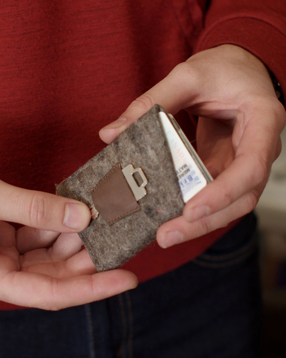 Man holding the Card Wallet sewing pattern from Thread Theory Patterns on The Fold Line. A wallet pattern made in felt, leather, Tyvek or Kraft-tex fabrics, featuring three pockets for up to six cards and folded cash, angled design allows for quick access