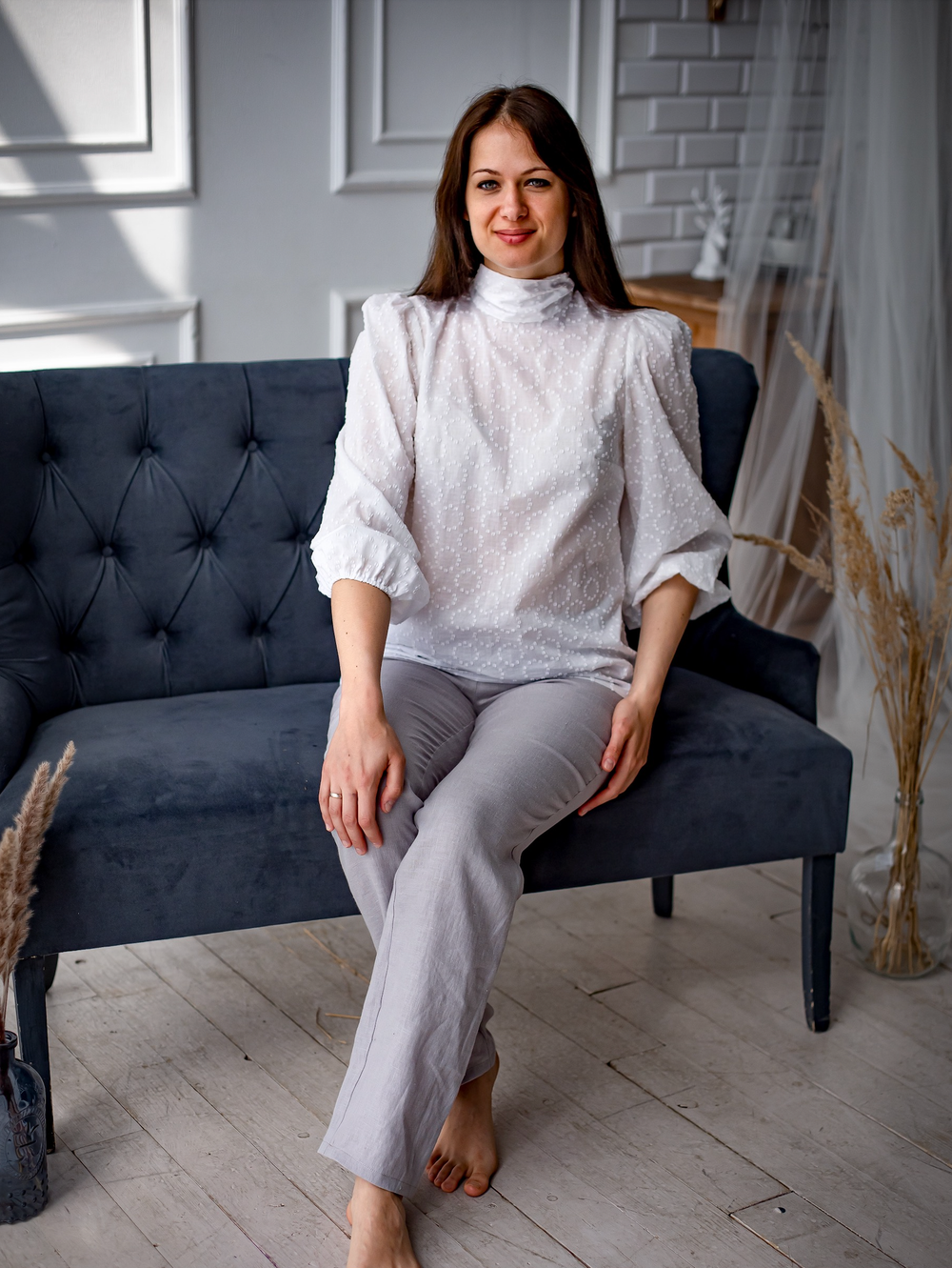 Woman wearing the Carrie Blouse sewing pattern from Kates Sewing Patterns on The Fold Line. A blouse pattern made in silk, linen or cotton fabrics, featuring bust darts, voluminous sleeves with elasticated cuffs and high collar which becomes a bow that ti