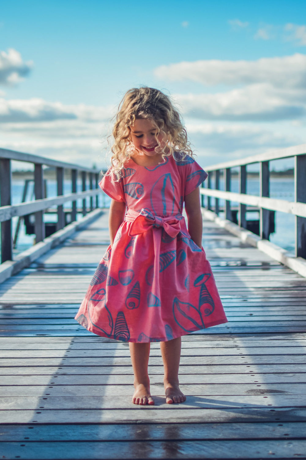 Child wearing the Children's Kinjarling Dress sewing pattern from Waves & Wild on The Fold Line. A dress pattern made in cotton poplin, cotton lawn and linen fabrics, featuring a pull on style, round neck, short grown on sleeves, in seam pockets and self-