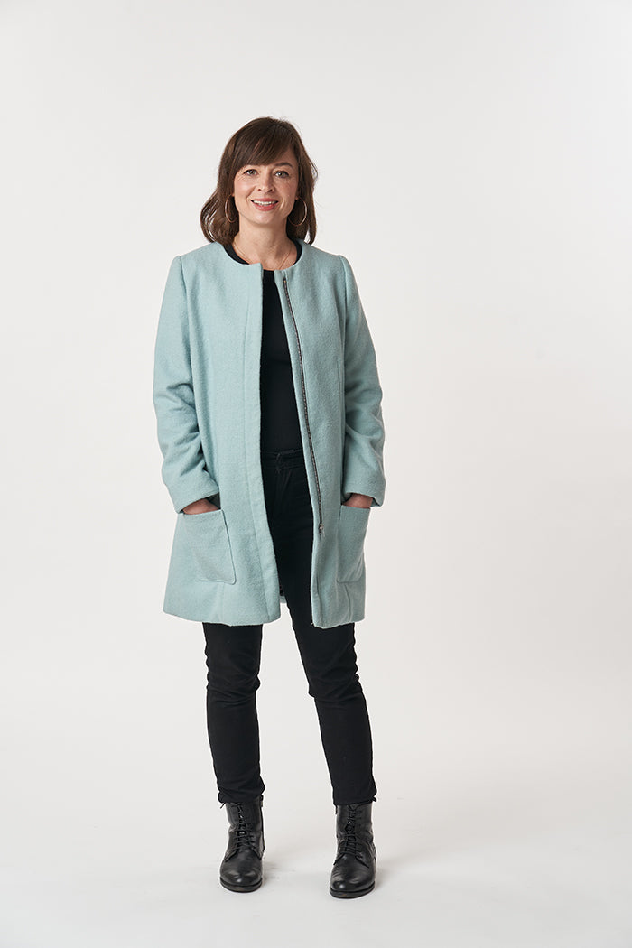 Woman wearing the Chloe Coat sewing pattern from Sew Over It on The Fold Line. A semi-loose coat pattern made in tweed, boucle, boiled wool, melton, jacquard or linen fabrics, featuring patch pockets, round neck, detachable scarf, either zipper or press s