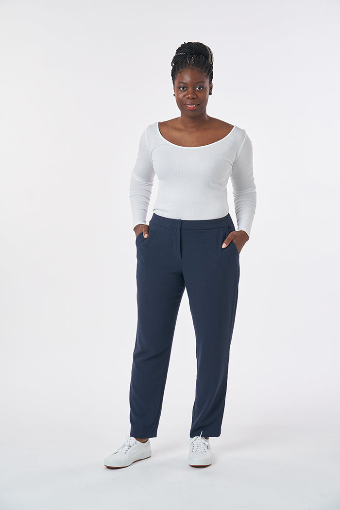 Woman wearing the Cigarette Pants sewing pattern from Sew Over It on The Fold Line. A trouser pattern made in crepe, and wool suiting fabrics, featuring a zip fly, curved waistband, flat front, slanted front pockets, back waist darts, tapered leg, and ank
