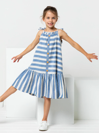 Child wearing the Children's Claudia Dress sewing pattern from Style Arc on The Fold Line. A dress pattern made in rayon, linen or cotton fabrics, featuring an A-line shape, spaghetti strap ties, front and back neck ruffle, hem frill, knee length, and fau